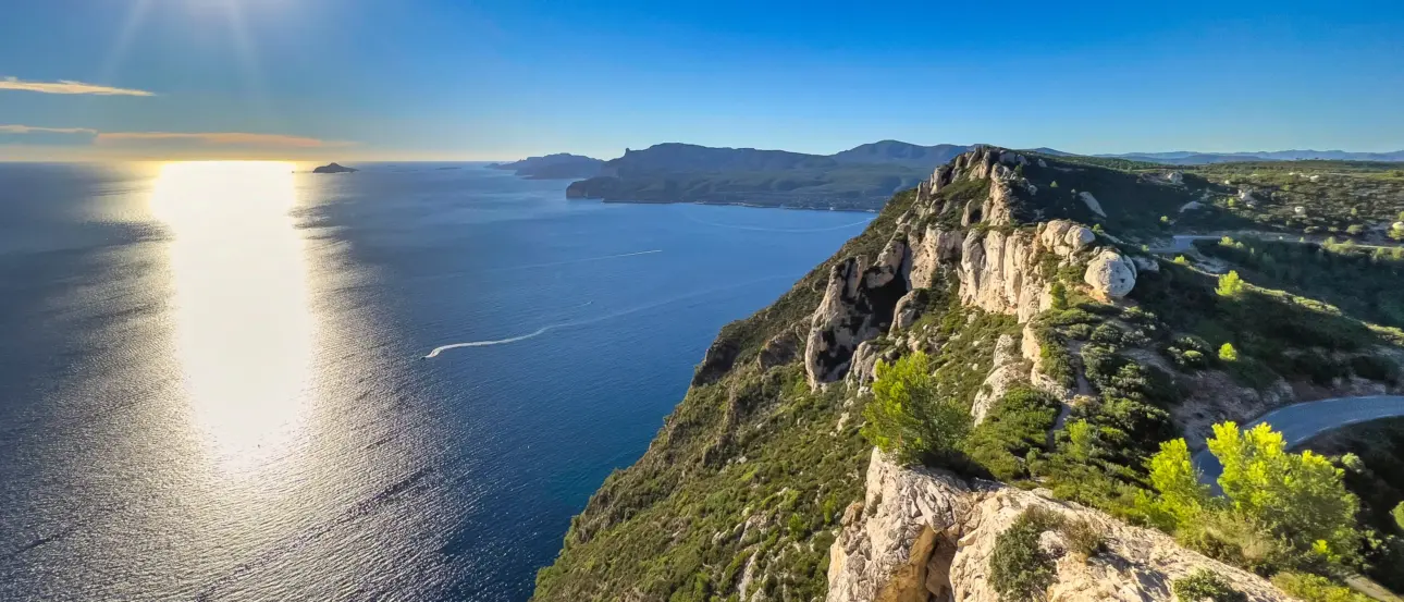 Eine steile Klippe ragt ins Meer, im Hintergrund ist ein sonniger Himmel
