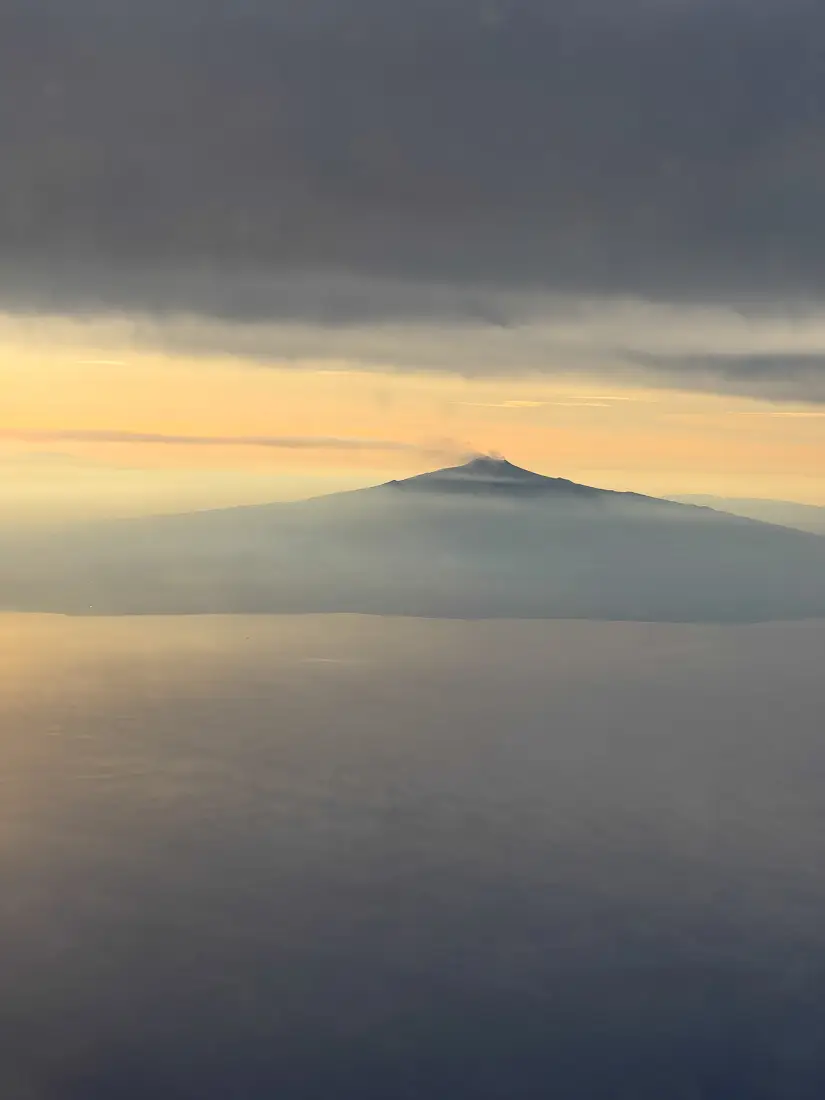 Ein Berg ragt über die Wolken hinaus während des Sonnenuntergangs.