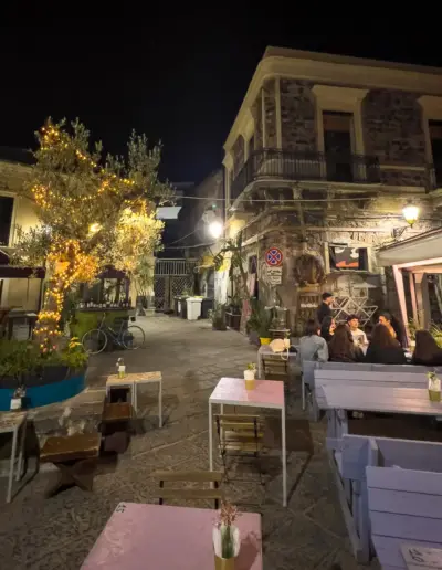 Ein mediterraner Platz bei Nacht mit Tischen und Menschen