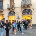 Eine Gruppe von Menschen steht vor einem Geschäft mit farbenfrohen Fenstern.