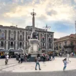 Ein Brunnen mit einer Statue in der Mitte eines Platzes, umgeben von Menschen